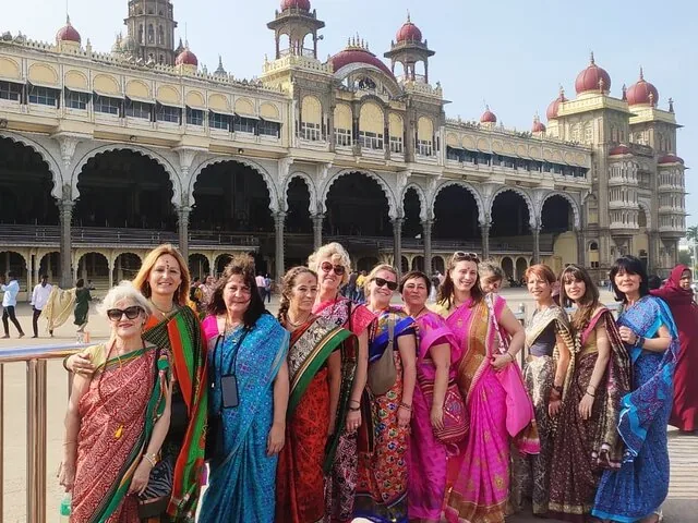 Eine Gruppe von Frauen in bunten Saris vor dem Mysore-Palast.