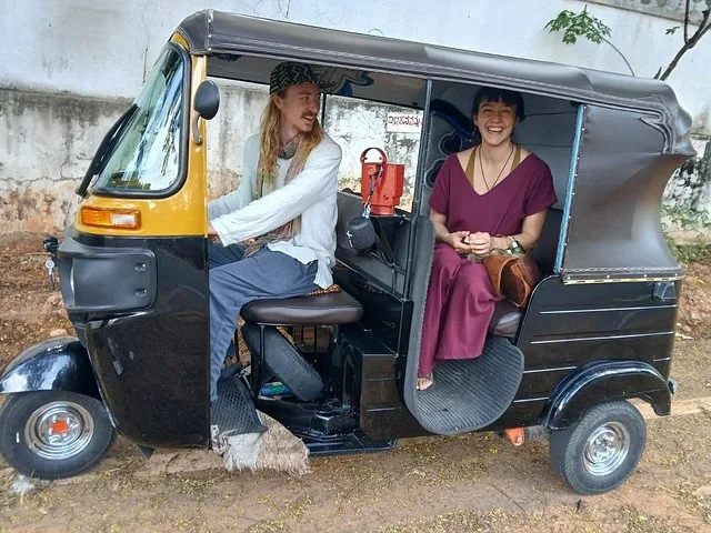 Coppia che si gode un giro su un tradizionale auto-risciò nero e giallo.