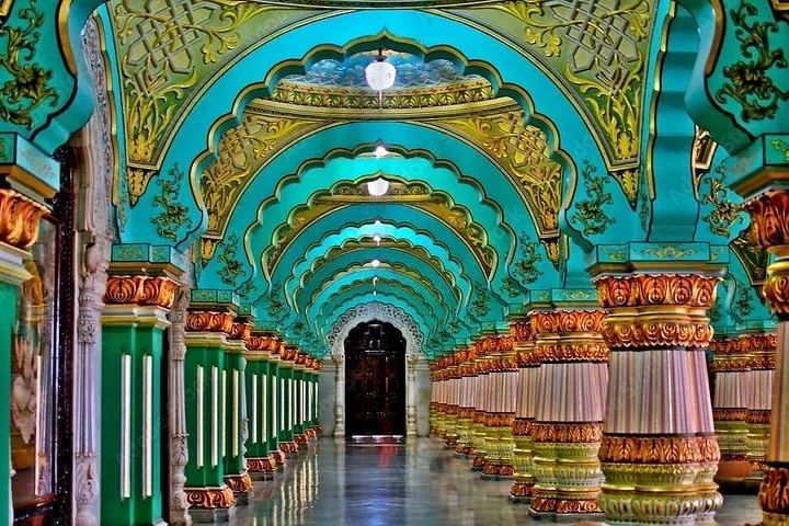 Innenansicht des Mysore-Palastes mit türkisfarbenen Bögen und verzierten goldenen Säulen.