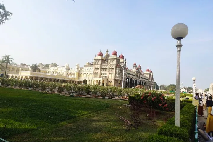 Fernsicht auf den Mysore-Palast von den Gärten aus mit umhergehenden Menschen.